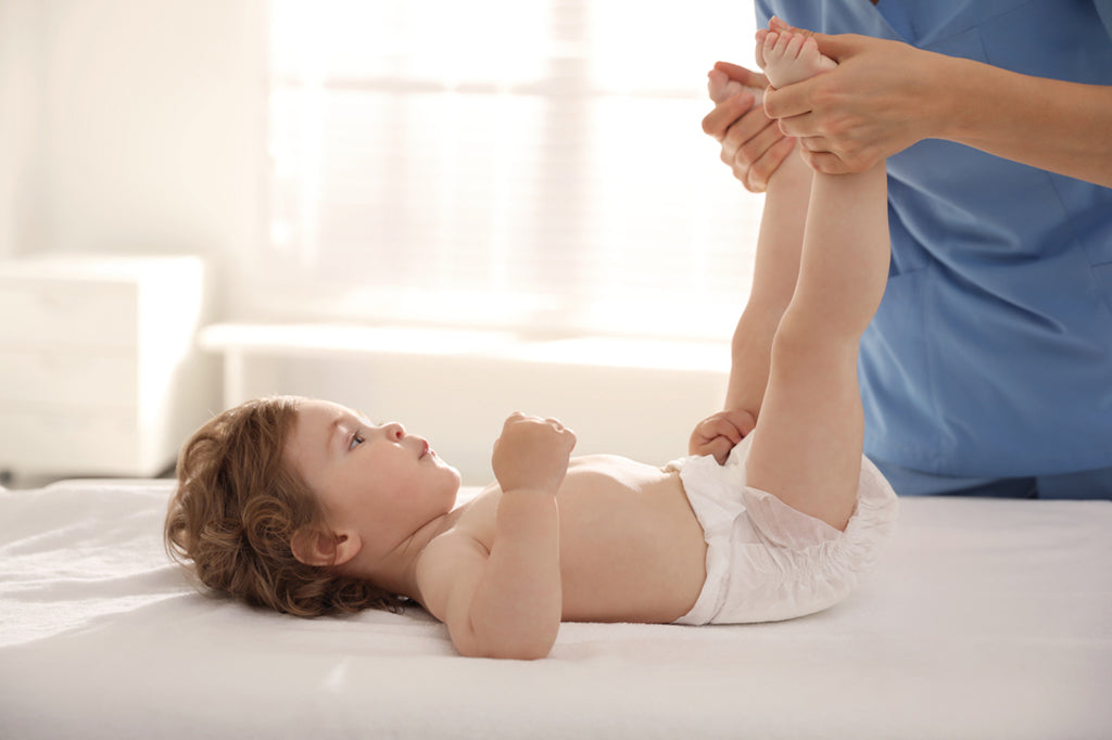 orthopedist examining little baby on bed
